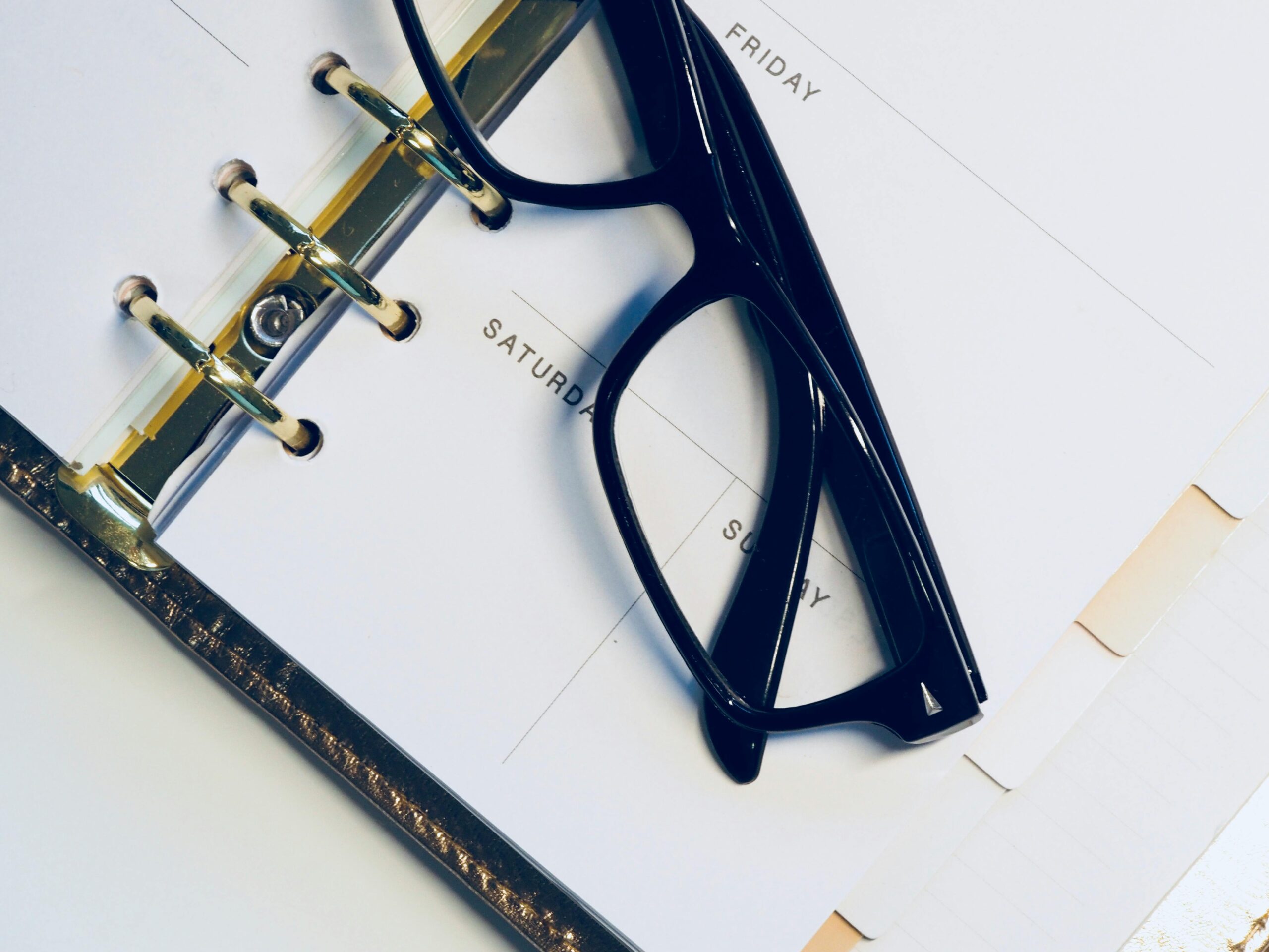 Close-up of eyeglasses resting on an open planner highlighting the weekend.